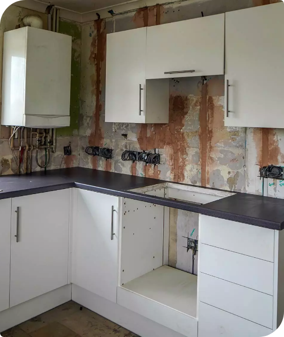 A kitchen under renovation with white cabinets and an unfinished wall.