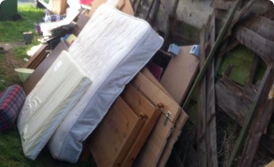 A pile of discarded mattress and debris left outdoors.