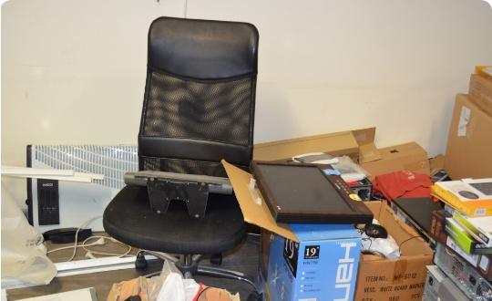 Office chair, clutter and boxes prepared for waste disposal.