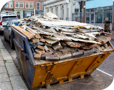 A construction dumpster filled with debris on a street.