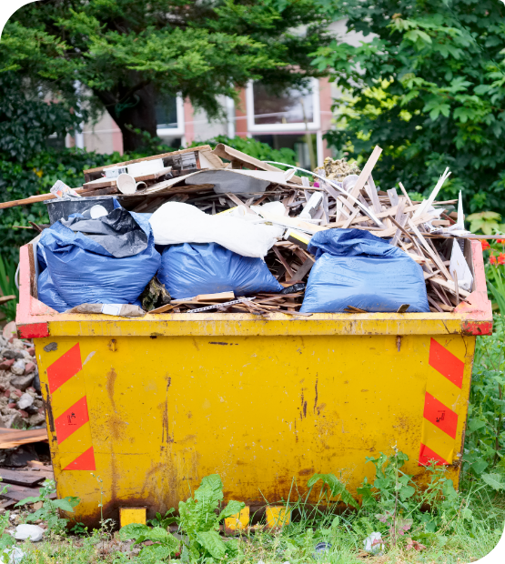 A yellow dumpster filled with construction debris and trash bags.