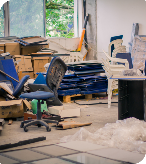 A cluttered office with scattered boxes, office furniture and supplies for disposal